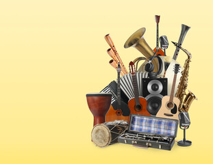 Group of different musical instruments on yellow background, space for text