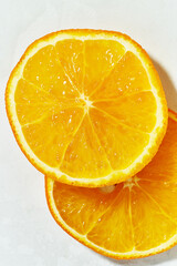 Macro view of an orange sliced into round slices on a white background.