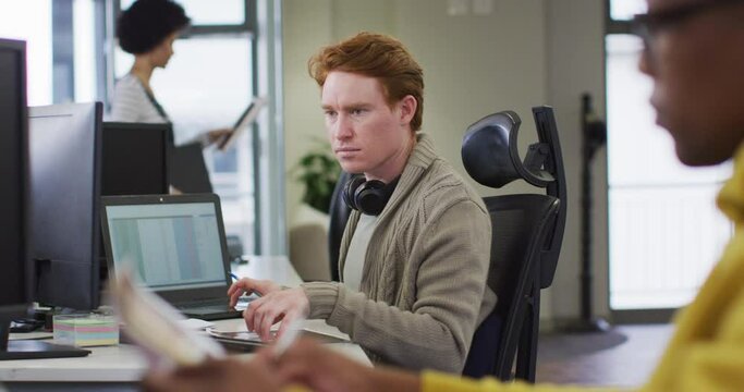 Portrait of caucasian creative businessman using computer in modern office