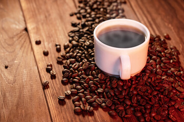 Warm cup of coffee and coffee beans on wooden background. Coffee cup and coffee beans on wooden table
