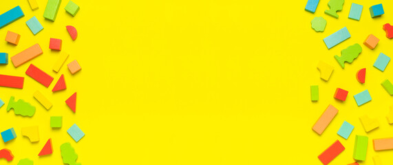 Multi-colored children's constructor made of natural wood on bright yellow background flat lay top...