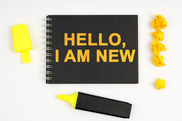 On the table is a marker, an exclamation mark and a notebook with the inscription - HELLO, I AM NEW