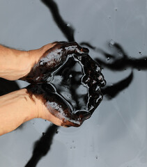 hands in crude black petroleum