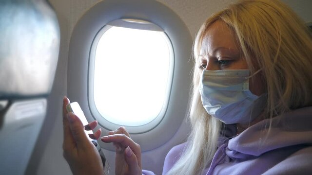 Woman wearing medical protective mask in airplane while flight. New normal travel during covid-19 pandemic situation in the world