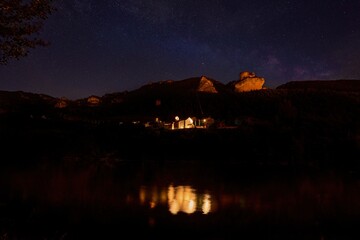 chapel of the cemetery of Les Vignes in the Gorges Du Tarn in France at night with reflection in the river Tarn and milky way in the night sky