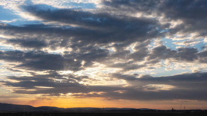 Panorama view on a moody yellow sunset between the clouds sky