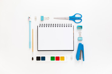 Top view of modern white blue office desktop with school supplies and stationery on table around empty space for text. Back to school concept flat lay with mockup