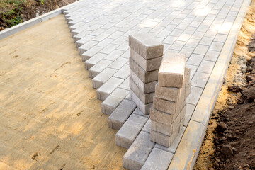 Top view of the edge of surface with laid gray paving slabs. Surface with sandy mixture is visible....