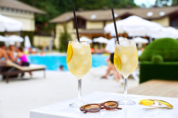 Two Glass of classic cocktail and sunglasses, at blue swimming pool. Vacation, summer, holiday, luxury resort concept.