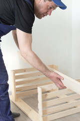 A carpenter assembles a wooden structure from slats. Carpentry work