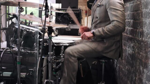 a man plays a drum kit at a party in a clipped suit