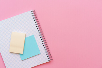 An open spiral notepad with stickers lying on top. Stationery on pink background