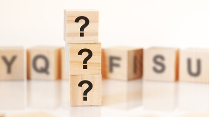 three question marks written on wooden cubes, white background