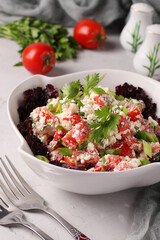 Tomato salad with cottage cheese, green onions, parsley and spices in a white bowl on gray background