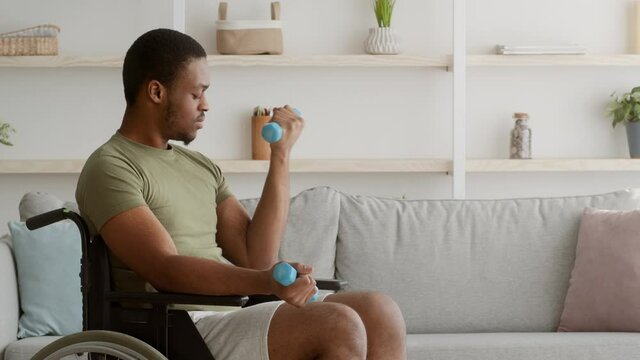 Disabled African American Man In Wheelchair Exercising With Dumbbells Indoors