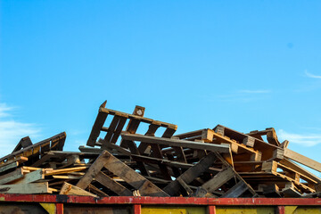 Old scrapped wooden shipping pallets in a randomly pile. Dumpster. Garbage removal