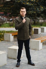 Portrait of a young handsome man, model of fashion, with modern hairstyle in urban background, wearing casual clothes.