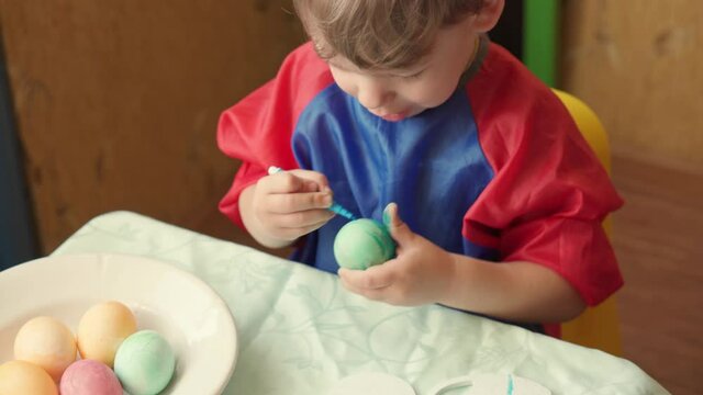 Happy Easter Holiday. Beautiful children paint decorate egg for traditional spring dinner at home. Little girl and boy playing fooling drawing easter eggs. Childhood, Education, celebration concept