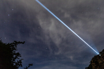 Laser-like lighthouse light and starry sky