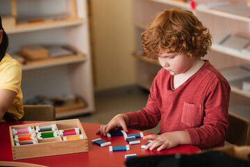 curly boy sorting colorful cards near girl in montessori school