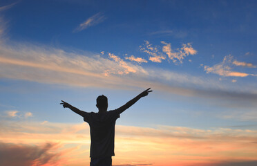 Fototapeta na wymiar Silhouette of man with open arms and with sky after sunset in background. Concept of success, victory and gratitude.
