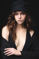 Girl on a black background. Low key. Nice young girl in a hat on a black studio background.