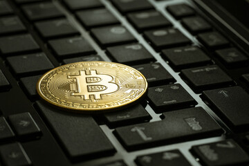 CLOSE UP OF A BITCOIN ON LAPTOP KEYBOARD. CRYPTO CURRENCY CONCEPT.