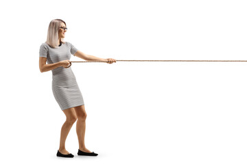 Full length profile shot of a young woman pulling a rope - obrazy, fototapety, plakaty