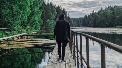 Man in the hood walks along the pier