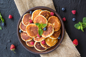 A healthy breakfast of cheese pancakes, berries, and honey. Creative atmospheric decoration