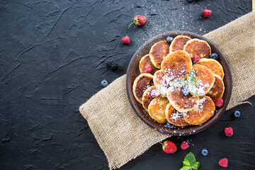 A healthy breakfast of cheese pancakes, berries, and honey. Creative atmospheric decoration