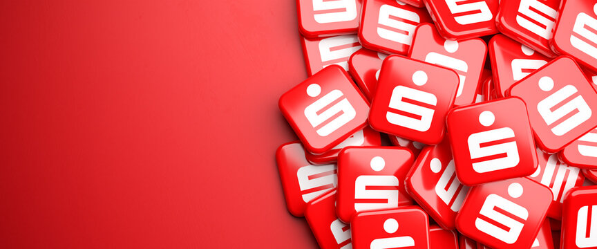 Logos of the German savings banks Sparkasse on a heap on a table. Copy space. Web banner format.