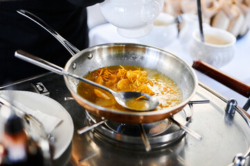 the chef prepares orange caramel on an open fire on the terrace of the restaurant