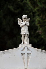 Small statue of a little angel girl at the gravestone at the old cemetery in Dalmatia