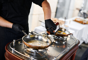 the chef prepares orange caramel on an open fire on the terrace of the restaurant
