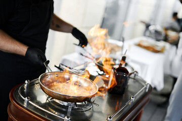 the chef prepares orange caramel on an open fire on the terrace of the restaurant