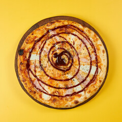 rustic bbq pizza with chicken and ham on wooden board and yellow background
