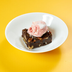 chocolate brownie with ice cream on white plate and yellow background