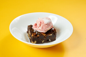 chocolate brownie with ice cream on white plate and yellow background