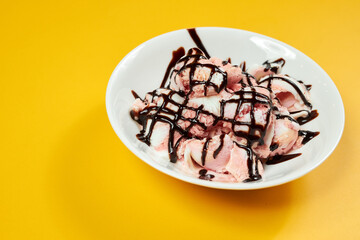 ice cream with chocolate syrup on white plate and yellow background