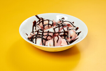 ice cream with chocolate syrup on white plate and yellow background