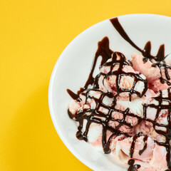 ice cream with chocolate syrup on white plate and yellow background