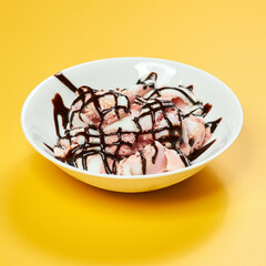 ice cream with chocolate syrup on white plate and yellow background