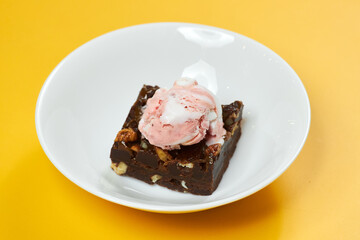 chocolate brownie with ice cream on white plate and yellow background