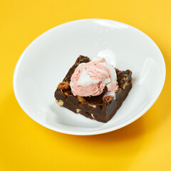 chocolate brownie with ice cream on white plate and yellow background