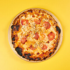 rustic pizza with tomatoes on wooden board and yellow background