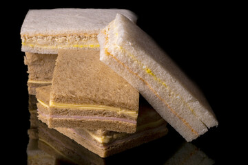 group of sliced bread crumb sandwiches on black reflective base and background.