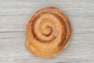 Overhead view of cinnamon roll donut is textured with glazed coating for a sweet treat delight
