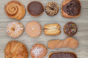 Dozen donuts arranged on a wooden surface for a great variety of choices for your sweet sugar or nut coated treat