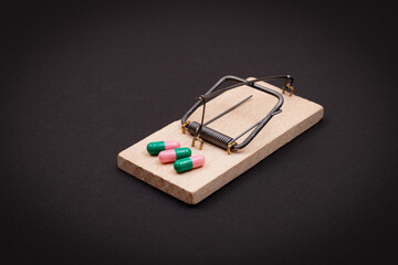 Pharmaceutical Addiction or Big Pharma Trap - Colored Pills or Capsules in Wooden Mousetrap on Black Background
